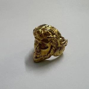 Macro detail of polished gold-plated stainless steel ring with a religious figure carving