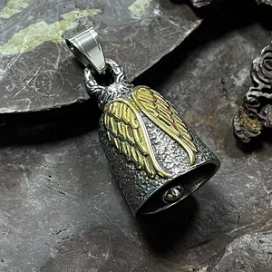 Détail macro d'une cloche gardienne en acier inoxydable avec ailes d'ange dorées