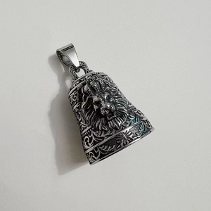 Macro detail of stainless steel bell pendant with crown lion and vintage arabesque texture