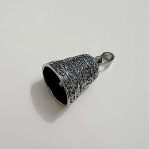 Macro view of vintage stainless steel bell pendant with carved floral arabesque patterns