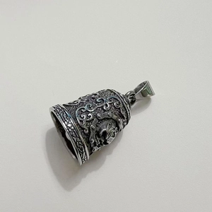 Macro detail of vintage steel biker bell with intricate dragon scales and hollow carvings