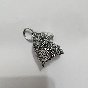 Detailed macro view of vintage stainless steel eagle bell pendant with intricate feathers