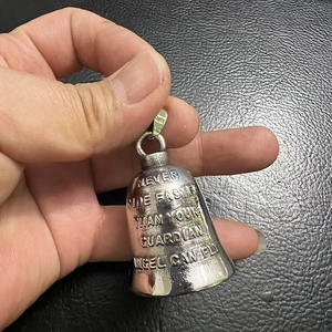 Detail of silver guardian bell with Never Ride Faster Than Your Guardian Angel Can Fly text