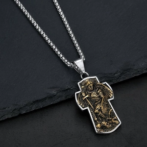 Détail du pendentif croix Saint Michel Archange sur chaîne en acier et fond de roche noire