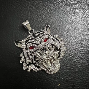 Macro detail of iced-out tiger head pendant with red eye accents on black leather