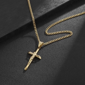 Detail shot of golden crucifix pendant with clear Jesus engraving on fine curb chain