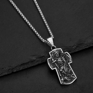 Collier pendentif Saint Michel en argent sur une surface en pierre noire texturée