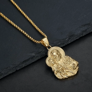 Close-up of golden Holy Family pendant with detailed relief on grey stone background