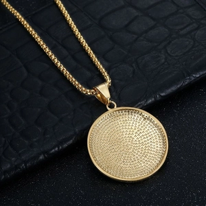Gros plan sur un pendentif médaille ronde plaqué or avec chaîne box sur fond sombre