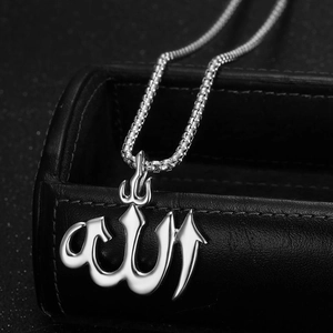 Detailed view of silver Allah pendant on pearl chain against black jewelry box background