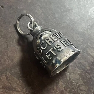 Macro detail of retro stainless steel guardian bell with engraved SCREW LET'S RIDE text