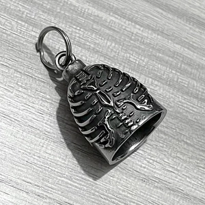 Detailed close-up of a vintage stainless steel skull skeleton bell pendant on wood