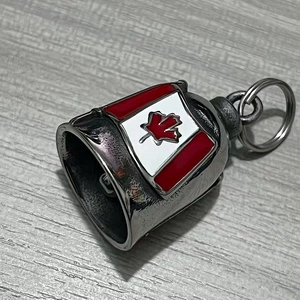 Close-up of vintage stainless steel bell keychain with red Canadian maple leaf flag