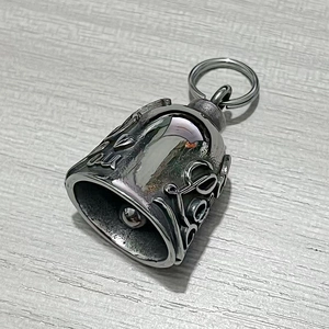 Gros plan d'un pendentif clochette de moto punk en argent avec reliefs gothiques gravés