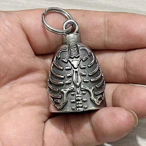 Macro detail of vintage stainless steel skeleton bell pendant with embossed ribcage