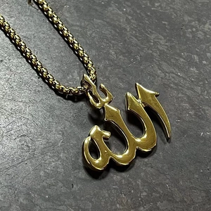 Close-up of a polished gold-plated Allah pendant with a robust box chain on stone