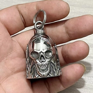 Detailed macro view of silver stainless steel skull bell pendant with flame engravings