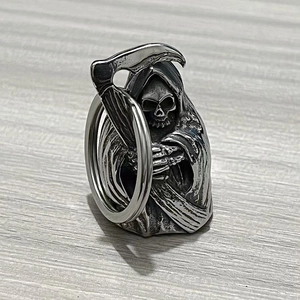 Detailed view of silver grim reaper skull pendant with scythe on wood background