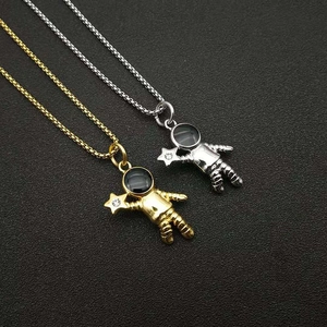 Détail macro des pendentifs astronaute or et argent avec petites étoiles brillantes sur chaînes