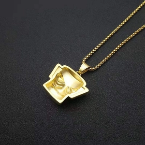 Macro detail of golden 3D Sanxingdui mask pendant on a textured black surface
