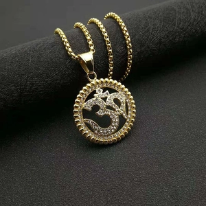 Collier pendentif Om doré avec cristaux blancs et bordure dentelée sur fond gris