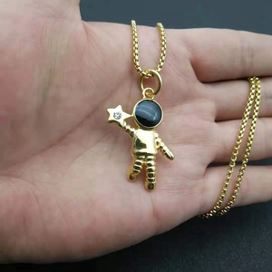 Collier astronaute doré avec zircon étoilé tenu en main pour visualiser la taille