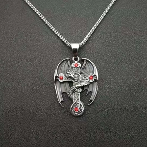 Close-up of gothic dragon cross pendant with red rhinestones on vintage metal chain
