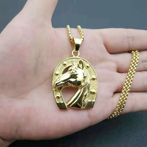 Golden horse head and horseshoe pendant necklace with circular link chain on hand