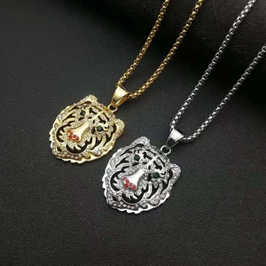 Détail de pendentifs tigre or et argent avec yeux verts et ornements en cristal