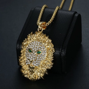 Pendentif tête de lion doré avec yeux verts et strass blancs sur une chaîne à billes