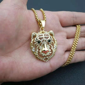 Vue macro d'un pendentif tête de tigre plaqué or avec cristaux de zircone en main
