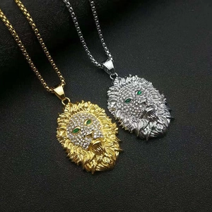 Détail de pendentifs tête de lion en or et argent avec cristaux et yeux verts brillants