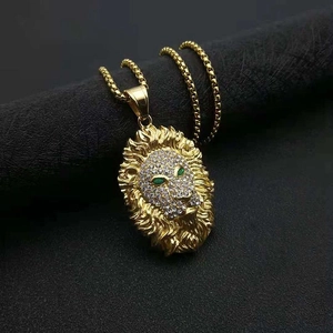 Détail du pendentif tête de lion plaqué or avec cristaux pavés et yeux verts brillants