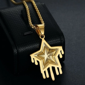 Détail macro du pendentif étoile dorée avec design fluide sur une surface en cuir noir