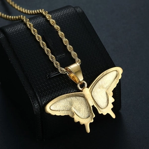 Detailed view of a gold-plated butterfly pendant necklace on a black textured jewelry box