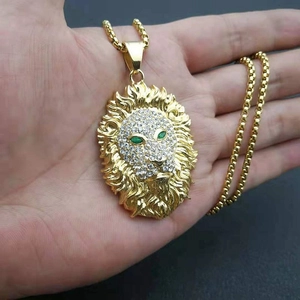 Détail du pendentif tête de lion doré avec strass scintillants et yeux verts