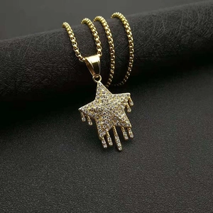 Détail d'un pendentif étoile hip hop doré serti de zircons avec effet de goutte de métal