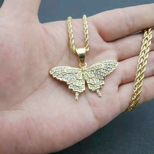 Detail of hip hop gold butterfly pendant with rhinestones on a thick rope chain