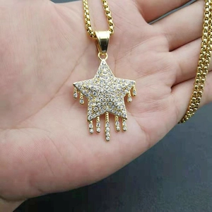 Détail du pendentif pentagramme doré serti de cristaux avec des détails de pompons