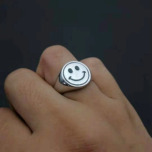 Macro shot of a stainless steel signet ring featuring a black enamel smiley face design