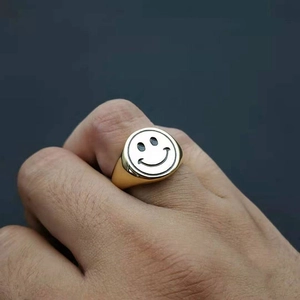 Close-up of gold plated stainless steel signet ring with a black enamel smiley face
