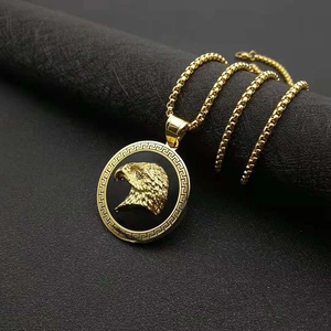 Detailed shot of a gold-plated eagle pendant with Greek key border on a square box chain