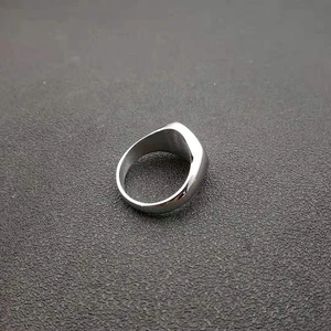 Detailed close-up of a silver-polished stainless steel signet ring on a matte surface