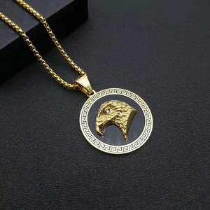 Macro view of gold-plated eagle head medallion with Greek key pattern and cubic zirconia