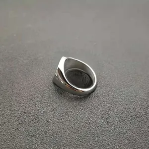 Detailed view of wide silver polished stainless steel ring on a textured grey surface
