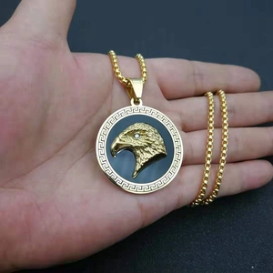 Detailed view of the gold-plated eagle head pendant with Greek meander border and box chain