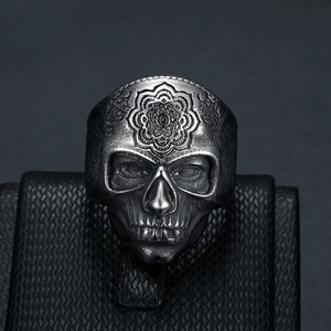 Retro punk style stainless steel skull ring with intricate floral engraving on black leather
