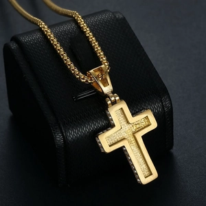 Close-up of gold cross pendant with frosted texture and zircon stones on black display
