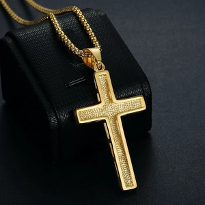 Gros plan du pendentif croix plaqué or avec insert texturé et chaîne à mailles carrées