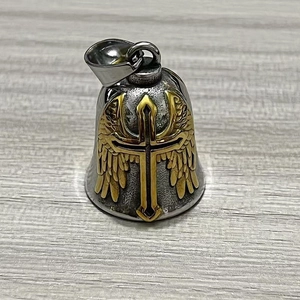 Nahaufnahme der Vintage-Biker-Glocke mit goldenem Kreuz und Flügeln auf Holz